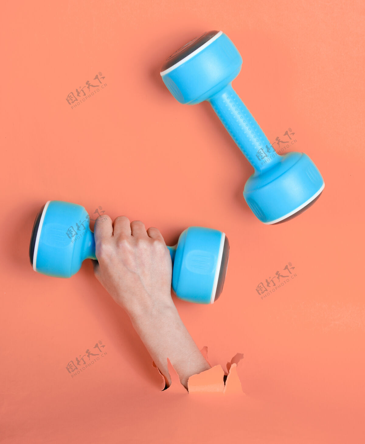 设备女手拿着蓝色塑料哑铃穿过撕破的粉色纸简约运动理念锻炼能量质量