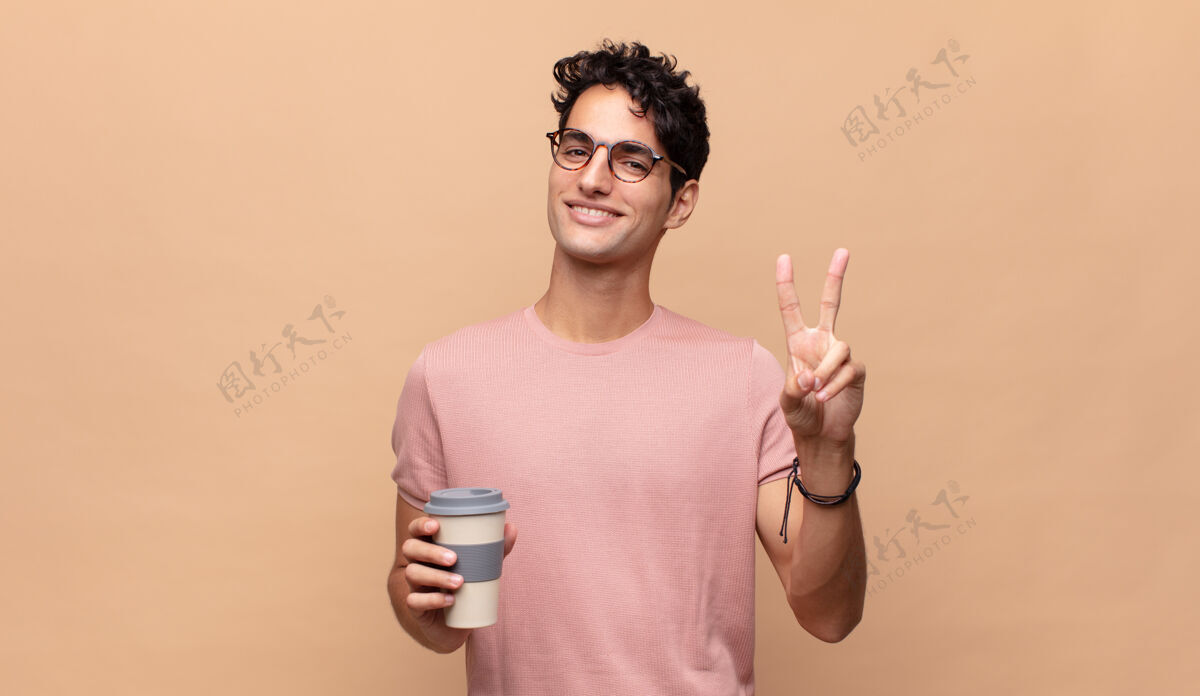 脸年轻帅哥端着咖啡 面带微笑 看上去很快乐 无忧无虑 积极向上 用一只手示意胜利或和平自由成功男人