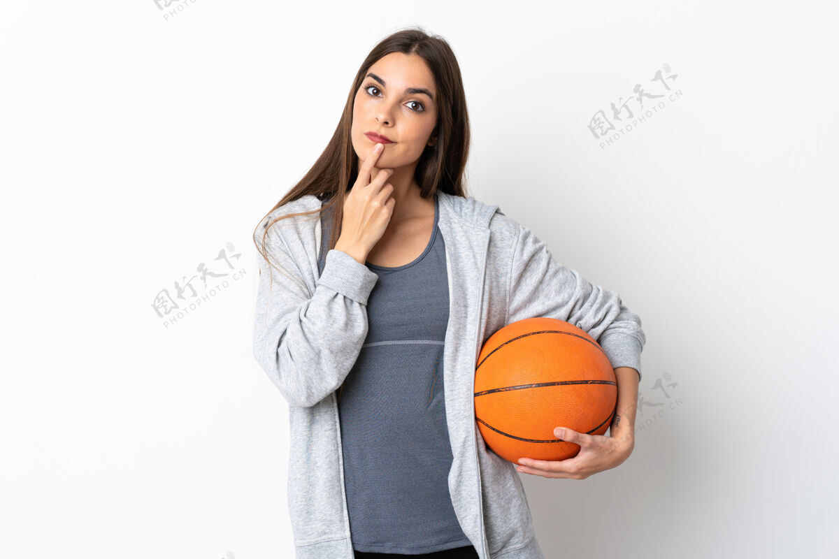 身体在白色背景上打篮球的年轻女子抬头时有疑惑年轻不确定困惑