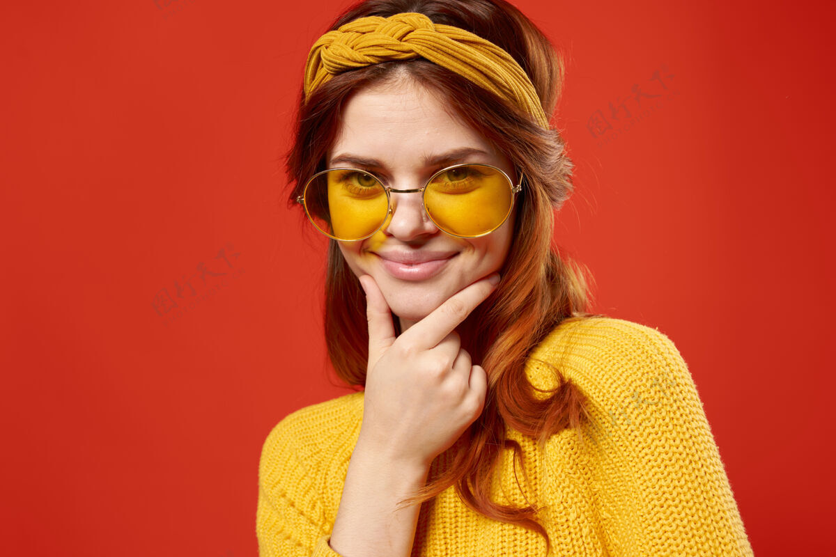 魅力情绪化的女人戴着眼镜黄色毛衣休闲装嬉皮红墙年轻休闲女性