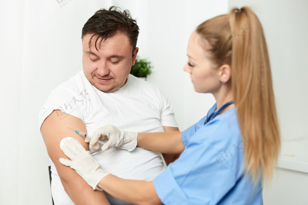 防护女医生把疫苗注射到一个男性病人的手臂上房屋室内成熟