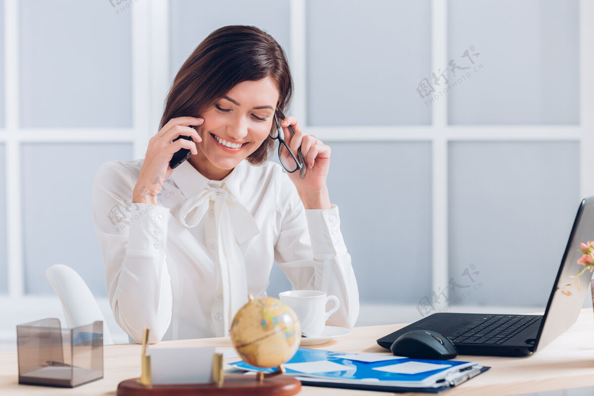 漂亮的女商人在办公室打电话和办公桌边工作个人经理电话