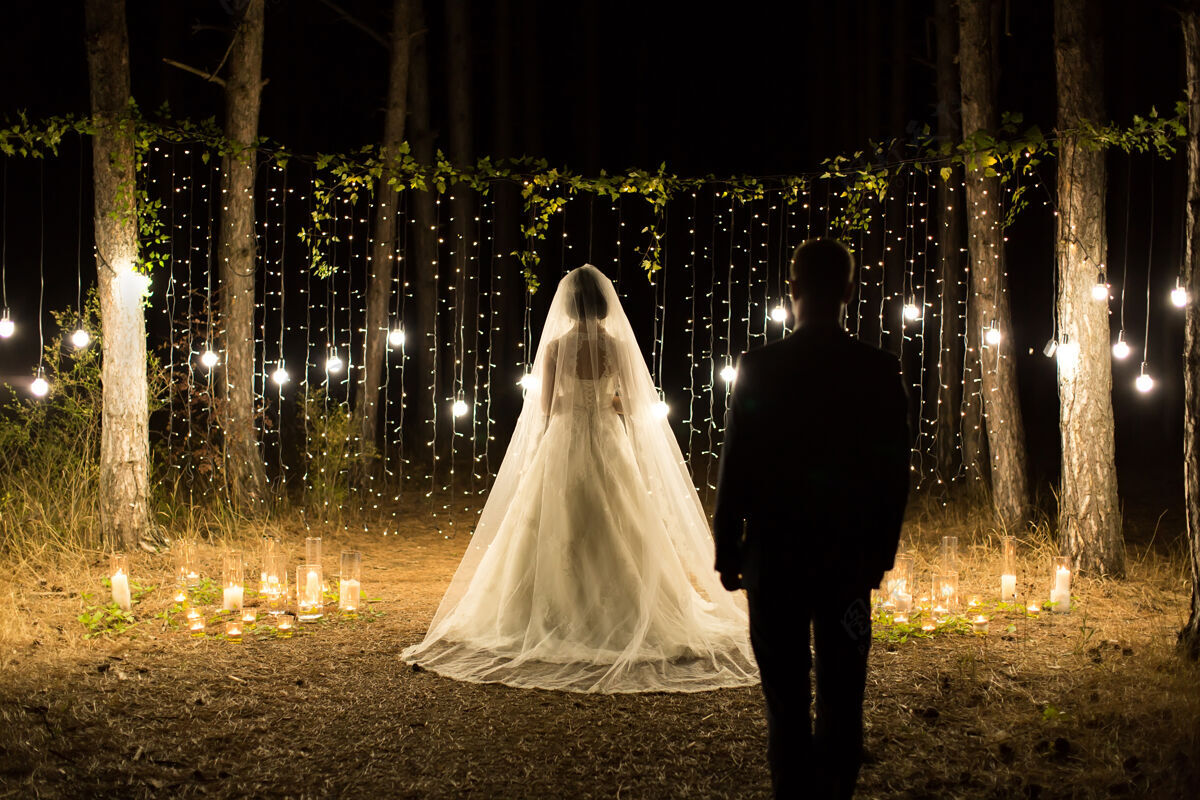 迷人婚礼夜间会议新婚夫妇中 新娘和新郎在针叶松林中点燃蜡烛和灯泡婚礼蜡烛萤火虫