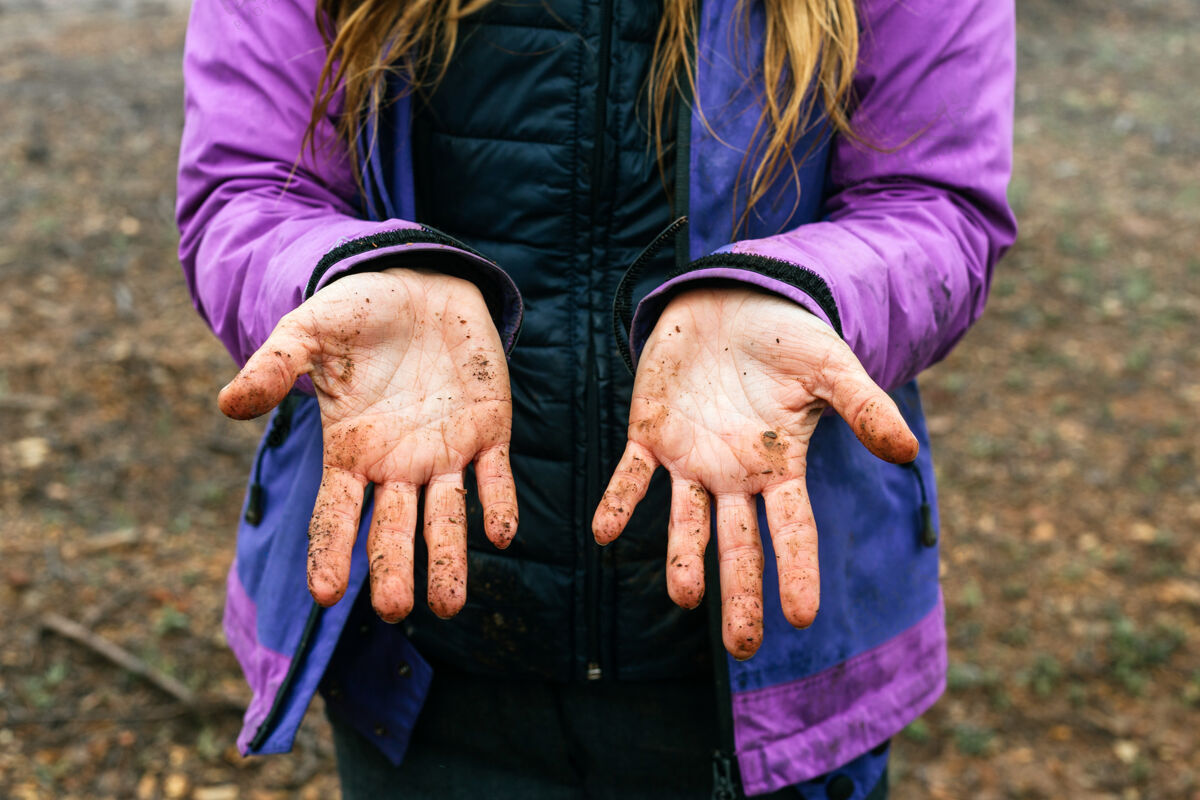 老年人一个无法辨认的女人的特写照片 在森林里徒步旅行时 她手掌上满是泥土冒险孩子外套