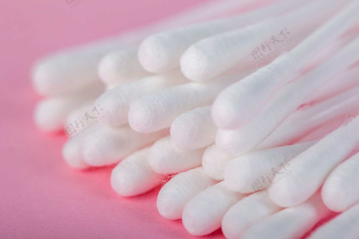 棉花在粉红色的地板上擦耳朵用的棍子拭子化妆品棒