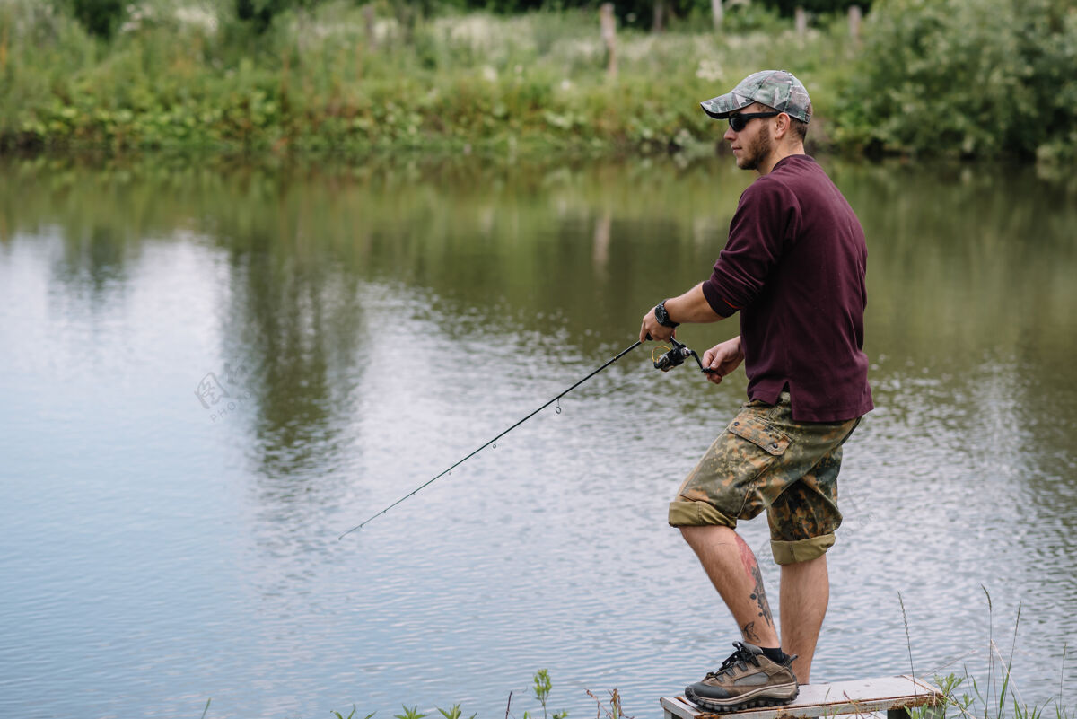 钓鱼一个渔夫拿着鱼竿在河岸上河流活动湖泊