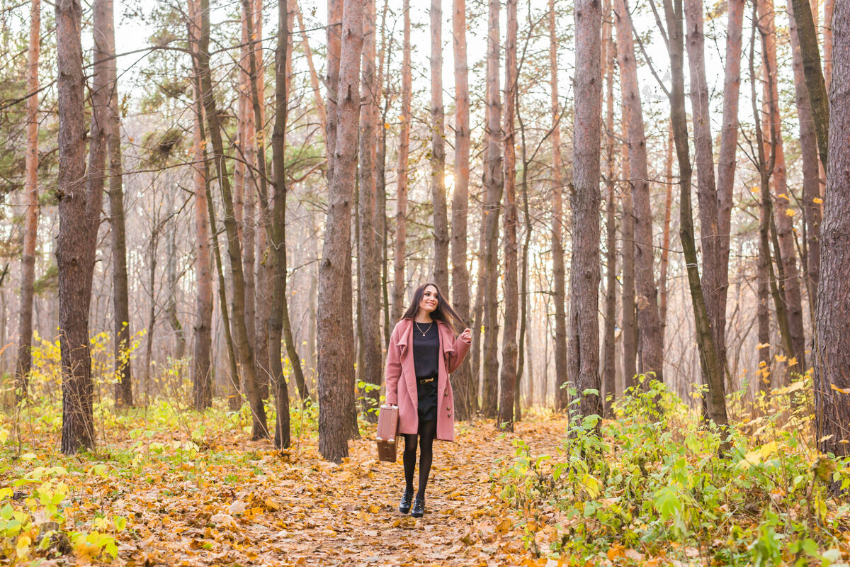 案例秋天 时尚 人的概念——女人带着棕色复古手提箱走过秋天的公园优雅公园快乐