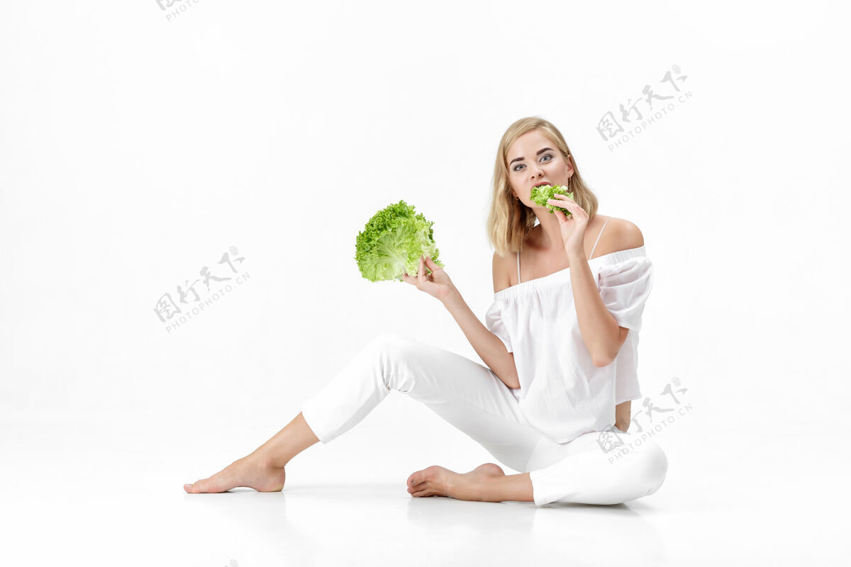 饮食一个穿着白衬衫的金发美女在白衬衫上吃着新鲜的蔬菜沙拉背景.健康还有节食人生活方式健康饮食