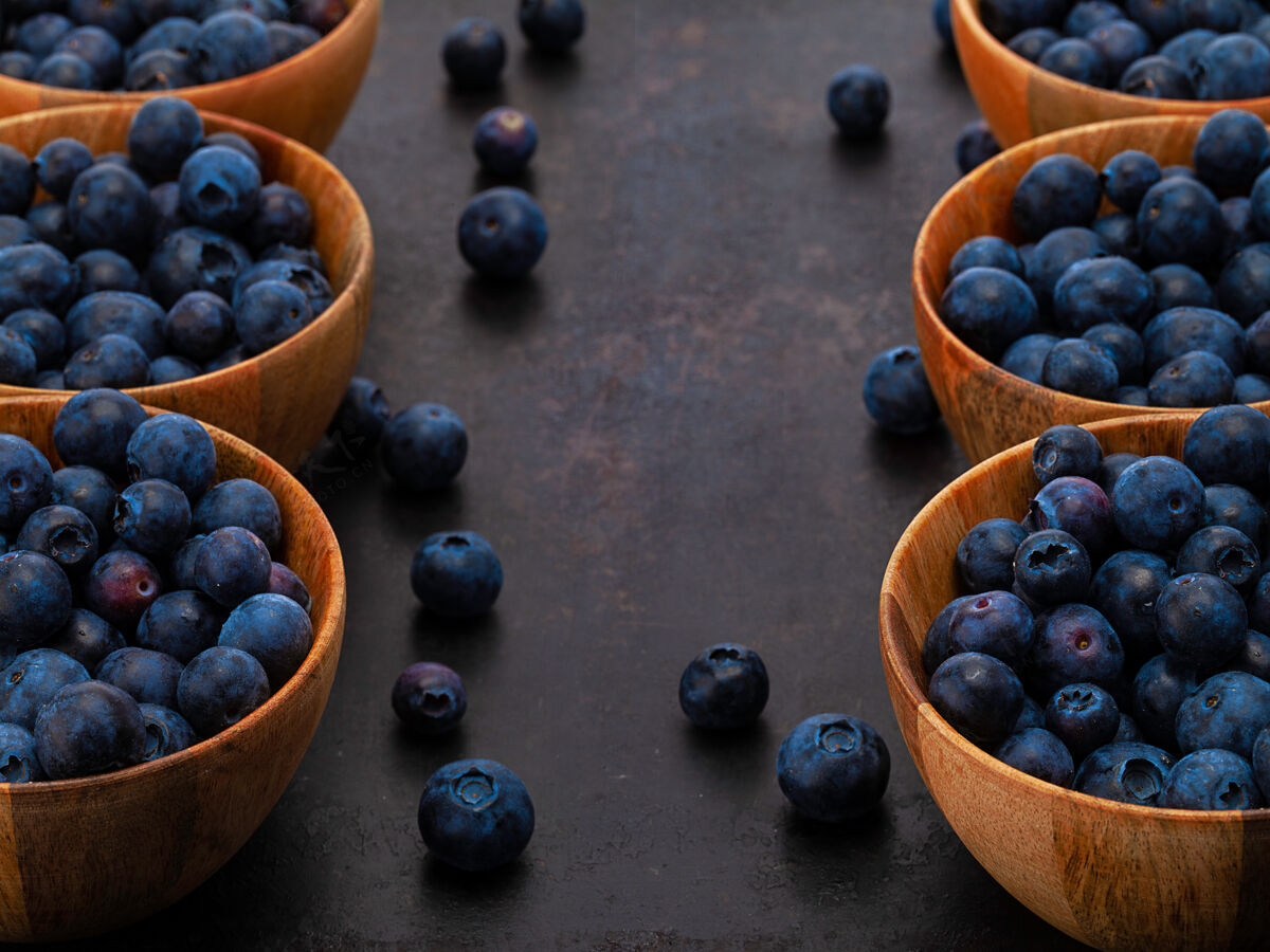 深色在古老的乡村背景上放着六个装蓝莓的木碗碗食物浆果