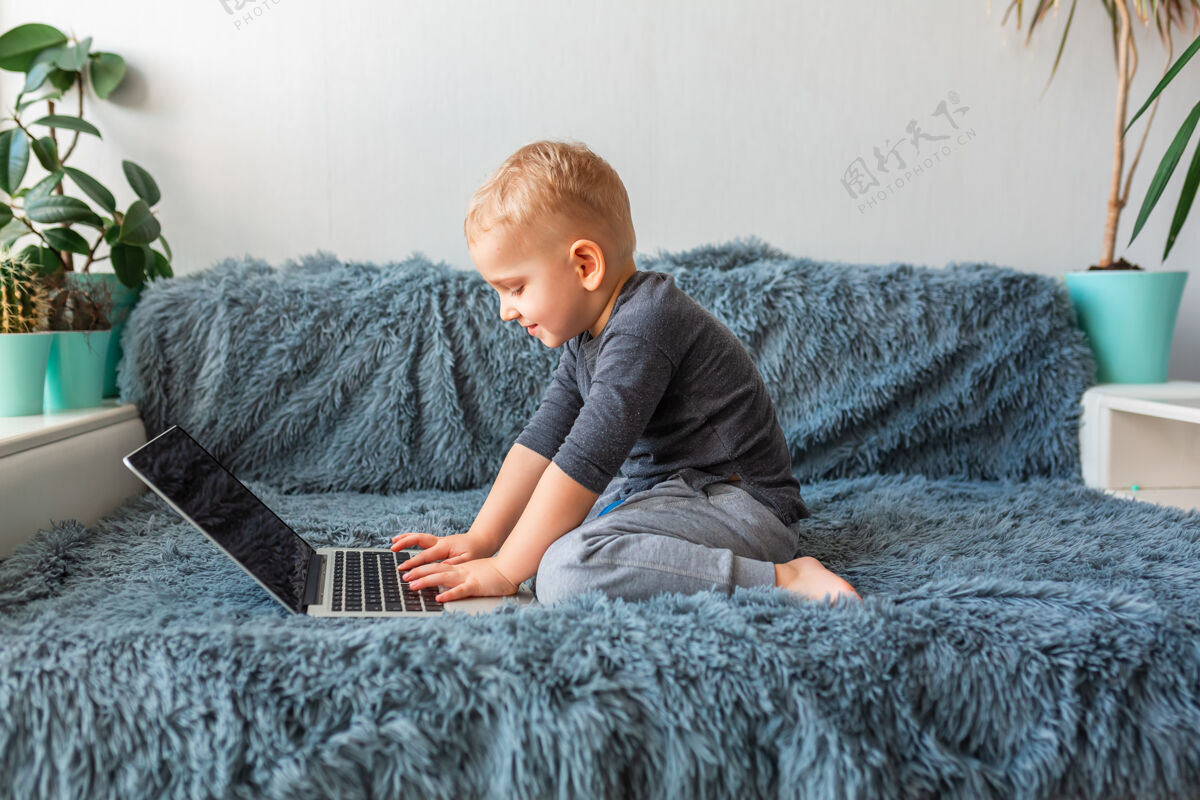 关系小男婴在家里的沙发上玩笔记本电脑电子学习 远程学习 远程交流的概念科技视频通话社交