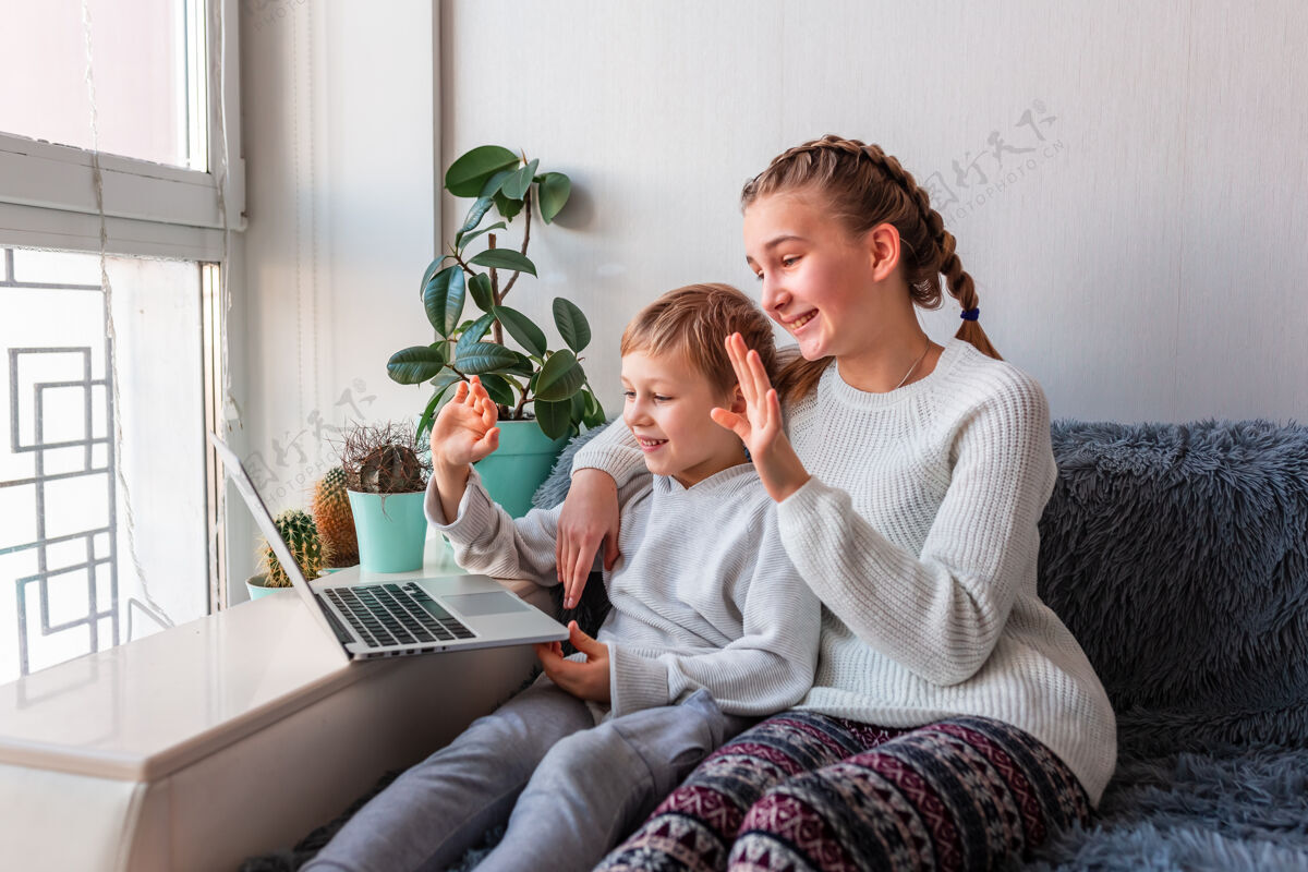 兄弟姐妹可爱的孩子在笔记本电脑上与祖父母视频通话留在家里 远程通信的概念一起玩游戏女孩