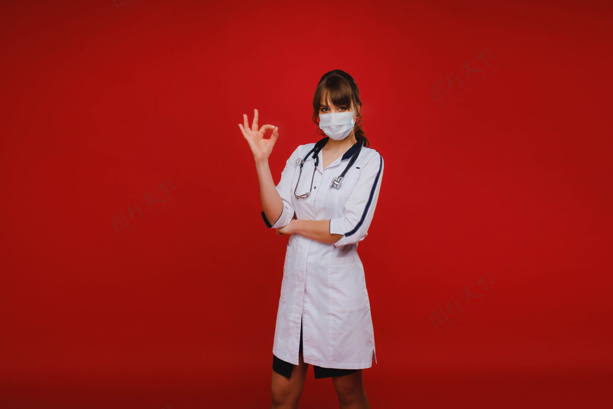 专家一位年轻的医生站在红色的背景上 举手示意一切都会好起来好吧那个医生没问题流行病穿着诊所