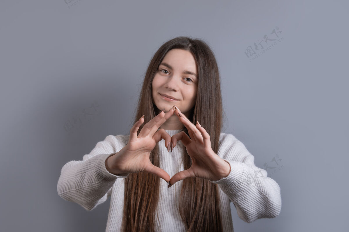 情人节一位年轻迷人的微笑女子用双手展示心形的肖像年轻爱快乐