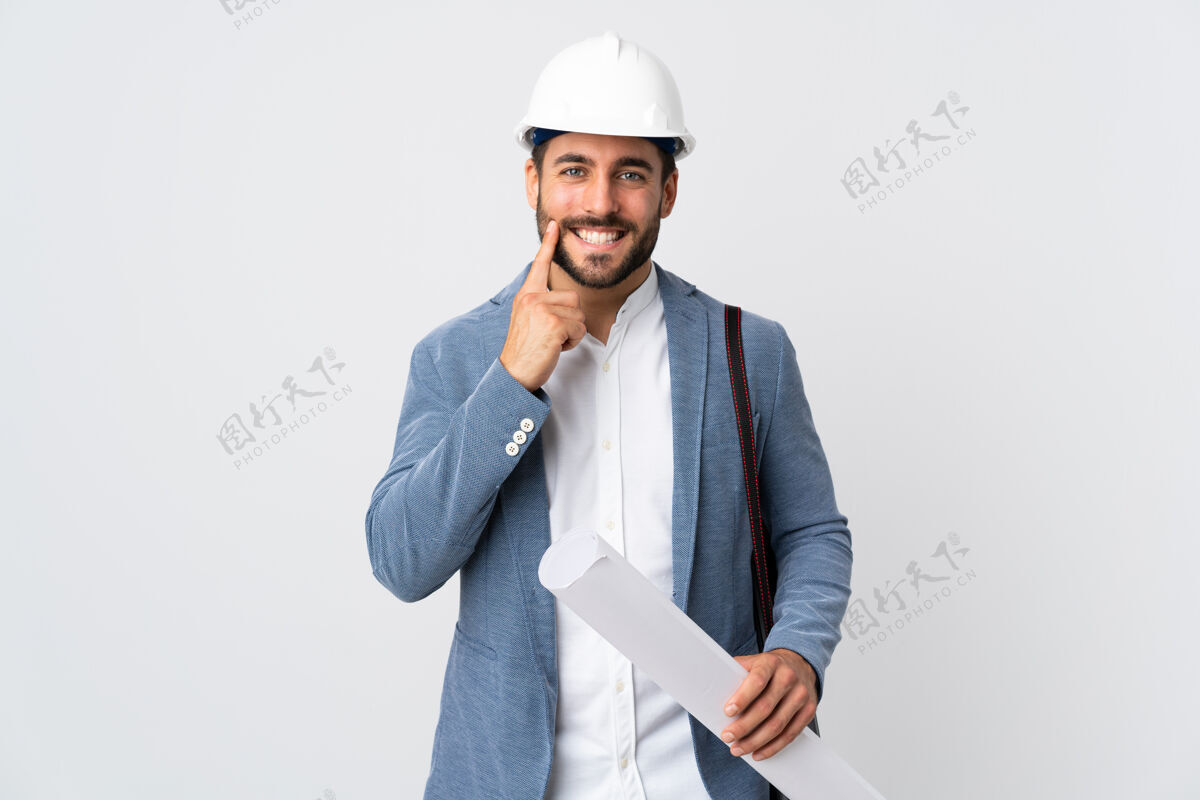 牙齿一个戴着头盔 拿着图纸的年轻建筑师孤立地站在白色的地板上微笑着 表情愉快学生肖像头部