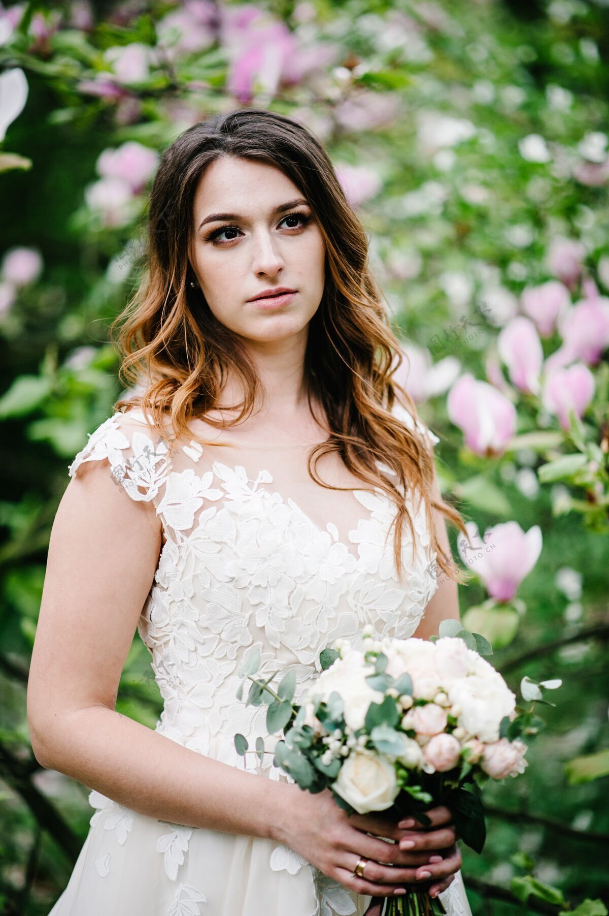 花美丽的新娘手持婚礼花束站在紫色的木兰花和紫罗兰花的背景上绿色.自然.户外.看侧边上部半身女性礼服粉色