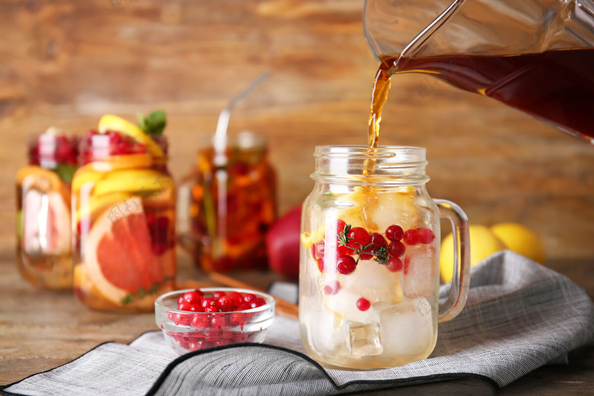 美味把美味的茶倒进桌上的玻璃罐里蔓越莓水果罐子