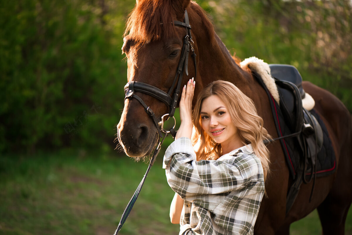 青少年美丽的姑娘牵着她的马和美丽温暖的夕阳在春天的森林里肖像农场活跃