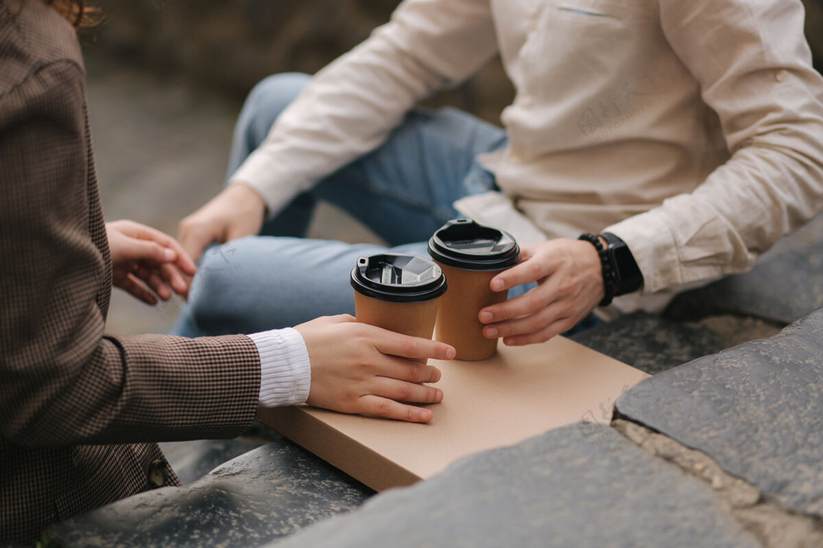 人微笑的情侣坐在室外的楼梯上 端着咖啡健康生活方式意大利