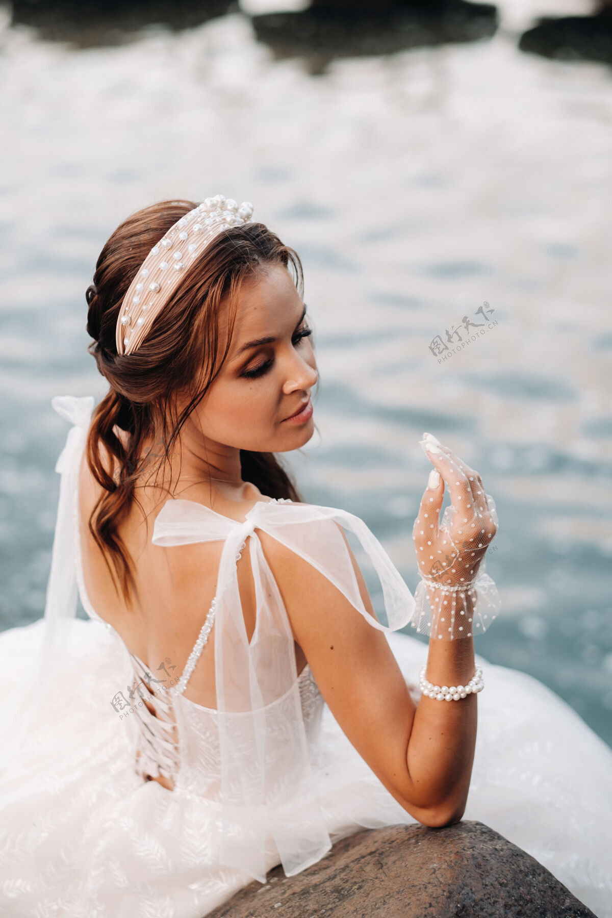 瀑布一位穿着白色礼服 戴着手套 赤脚的优雅新娘正坐在公园的瀑布旁 享受着大自然可爱自然年轻