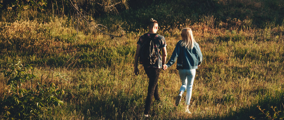 女性一对高加索夫妇手牵着手走在田野里的后景照片女孩空白自然