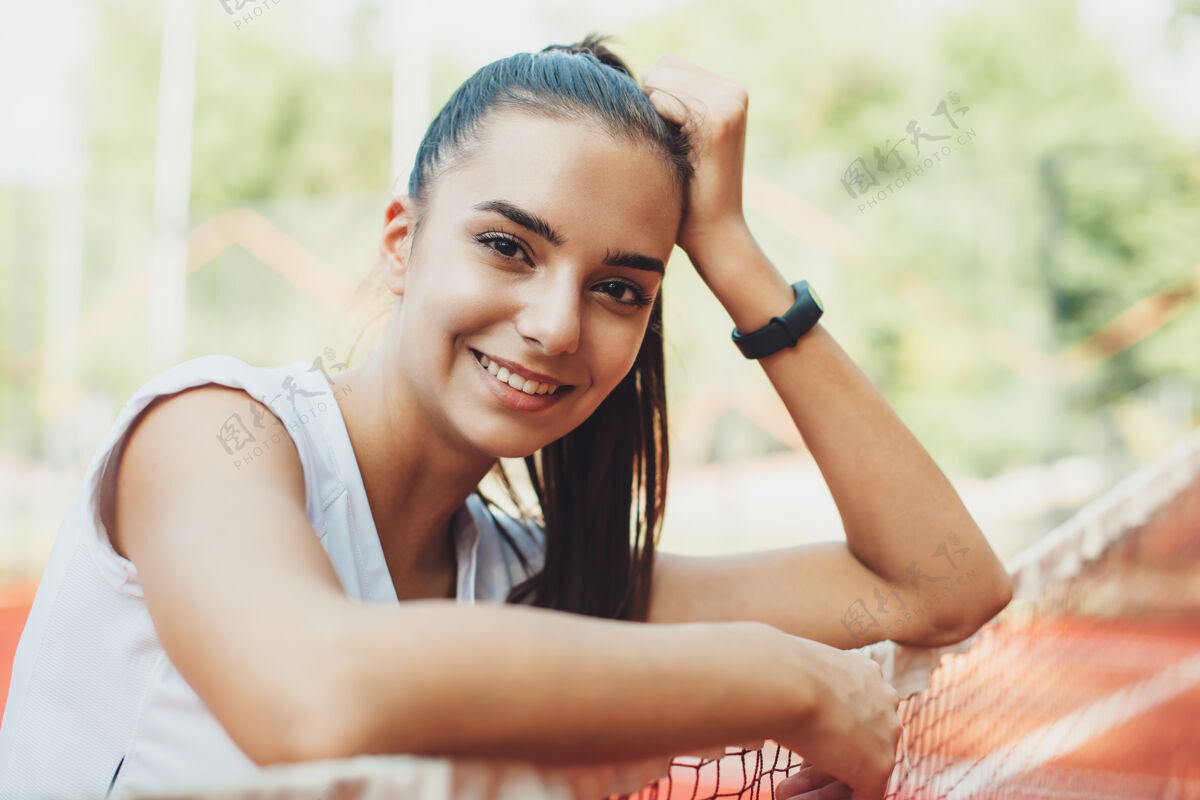 身体一位迷人的黑发年轻女子在户外晨练后休息时微笑的画像健身户外衣服