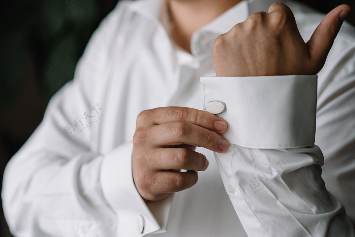 紧固件男手放在一件白色衬衫的表面 袖子上有袖扣和手表 拍下了特写镜头手经典面料