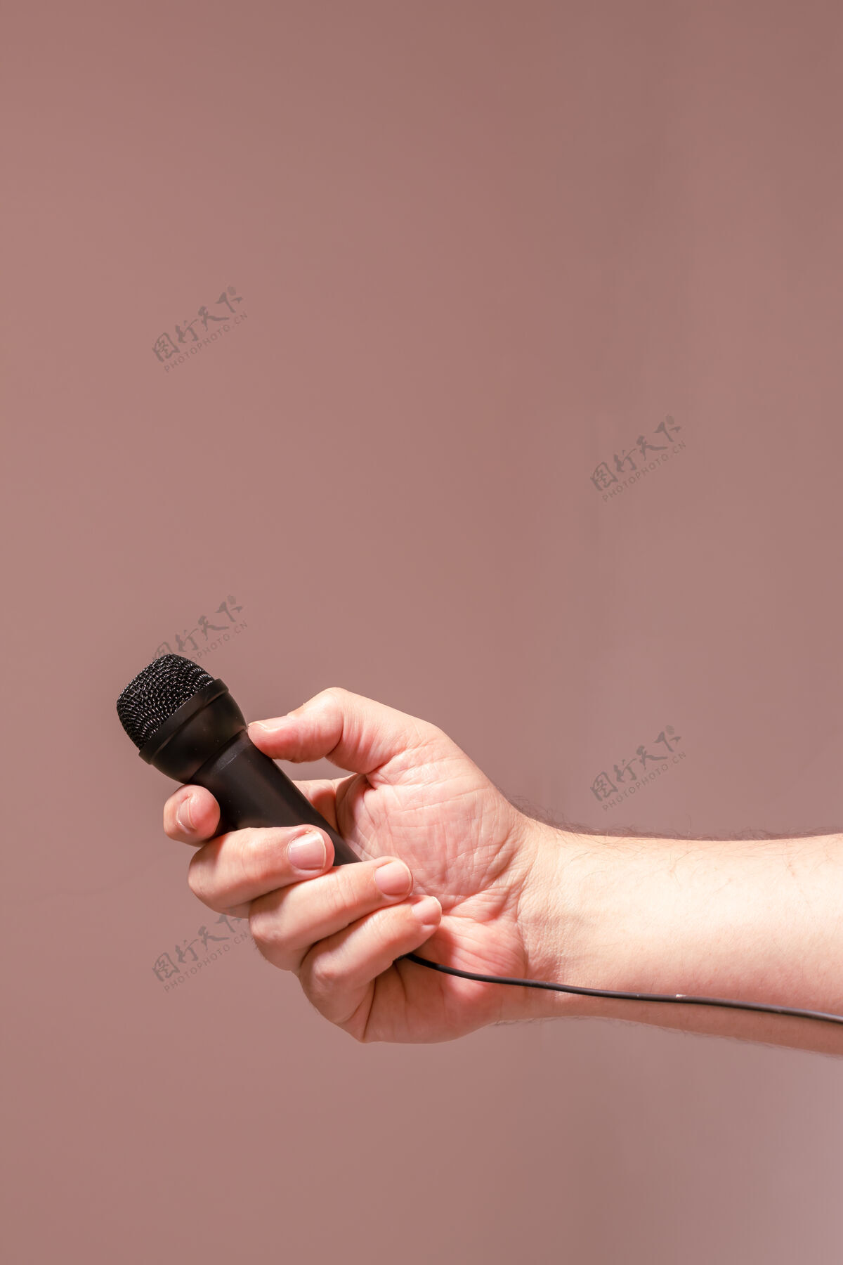 表演一个男人的手拿着一个黑色的麦克风.概念交流 采访 虚拟对话音频麦克风录音