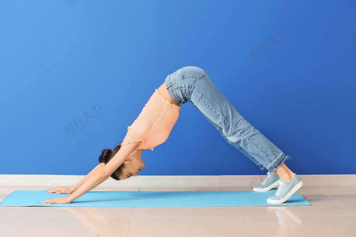 身体在彩墙边练习瑜伽的年轻女子墙壁放松姿势