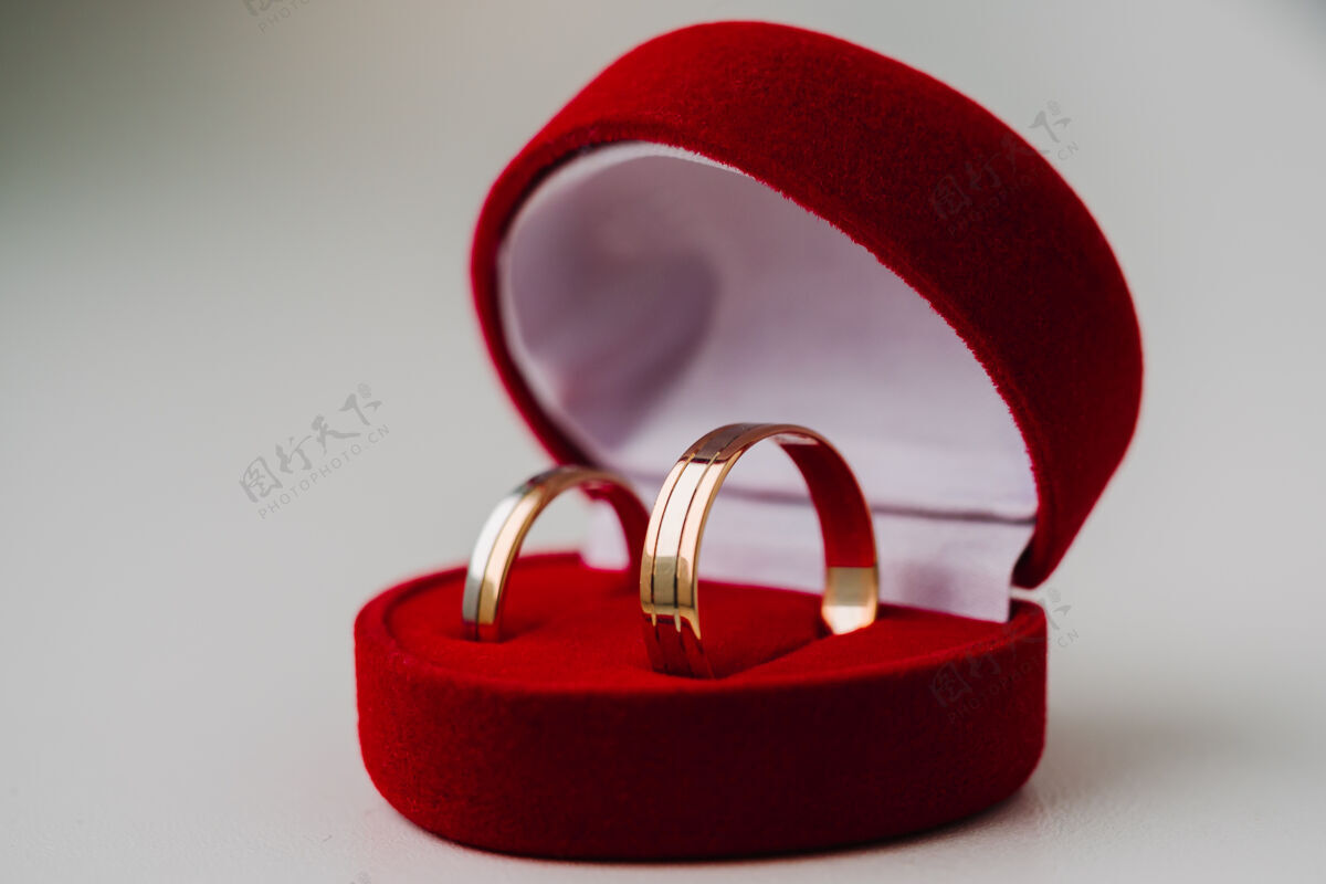 闪亮象征爱情的金色结婚戒指 以白色为背景 红色为心形情人节珠宝无人