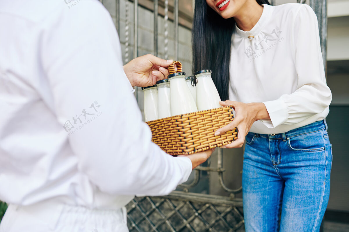 女微笑的年轻女子在家门口接受新鲜牛奶订单的特写镜头亚洲服务购物