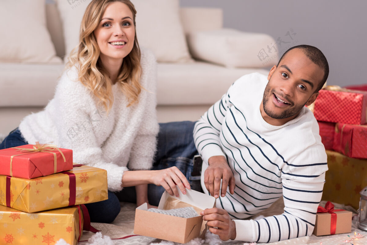 灯光圣诞节礼物不错快乐的年轻夫妇在礼物前打开行李 一边开心一边微笑男人手套白天