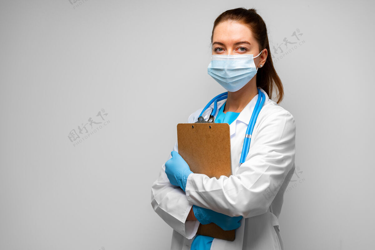药戴着医学面具的女医生站在灰色背景下 用剪贴板 肖像画外科医生制服面具