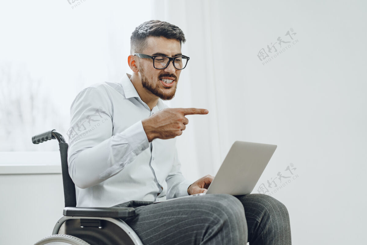 男性坐在轮椅上使用笔记本电脑的商人人电脑工作