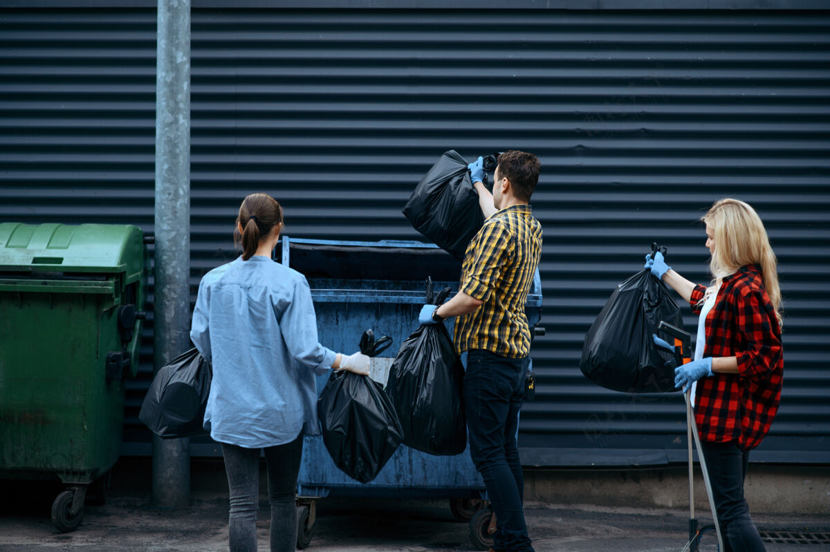 生态系统志愿者们把塑料垃圾袋放到户外的垃圾桶里 志愿者人清洁城市街道 生态修复 垃圾回收 生态关怀 环境清洁瓶子容器社区
