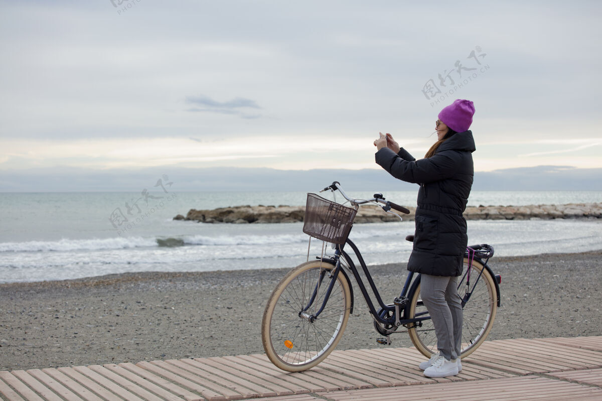 男人一个优雅的女人 在冬天的海边骑着自行车 用着手机 有空间发短信休闲水积极