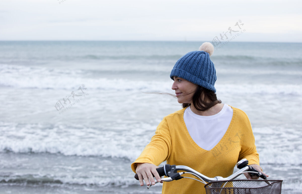 女性迷人的成熟女人骑着自行车在海滩上水天空休闲