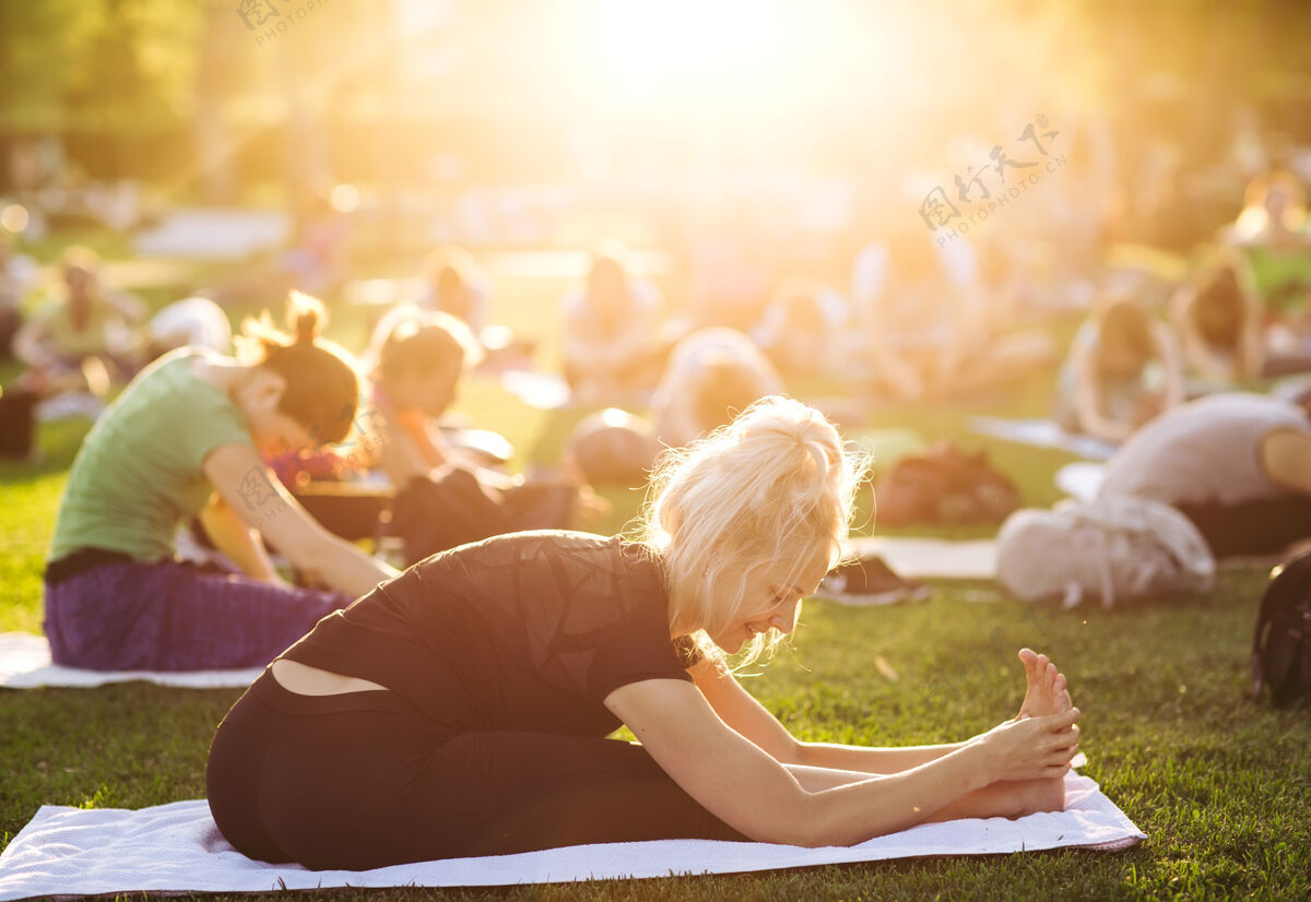 女孩一大群成年人在公园外参加瑜伽课年轻户外身体