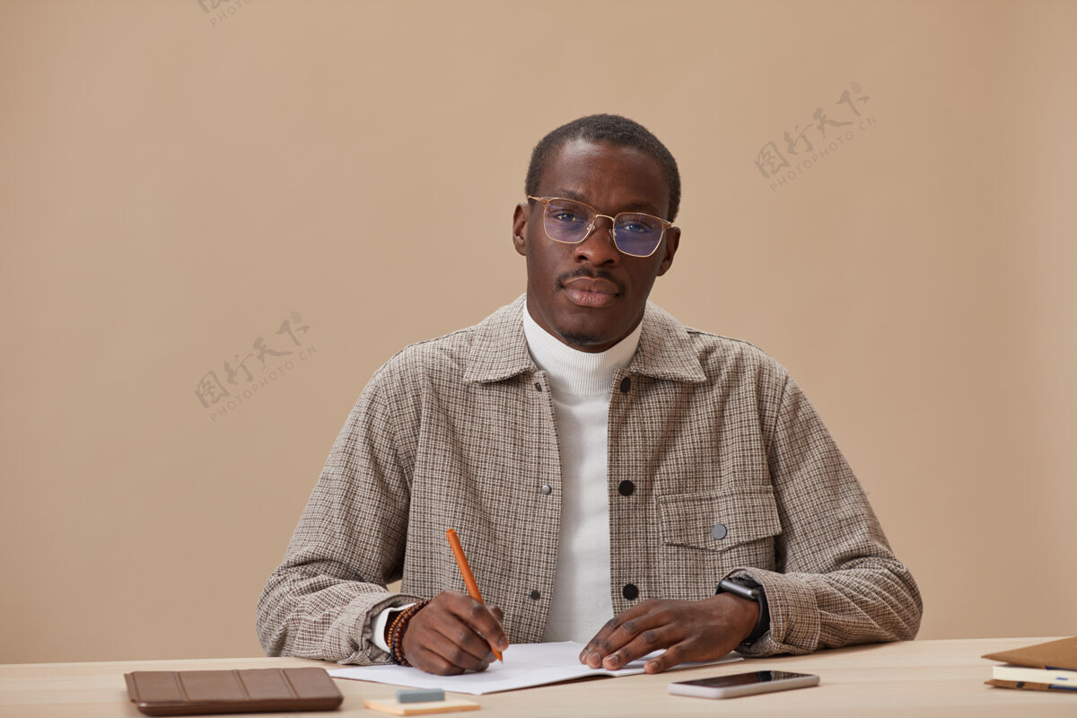 办公桌戴眼镜的年轻人坐在桌子旁看书学习的画像专注计划教育