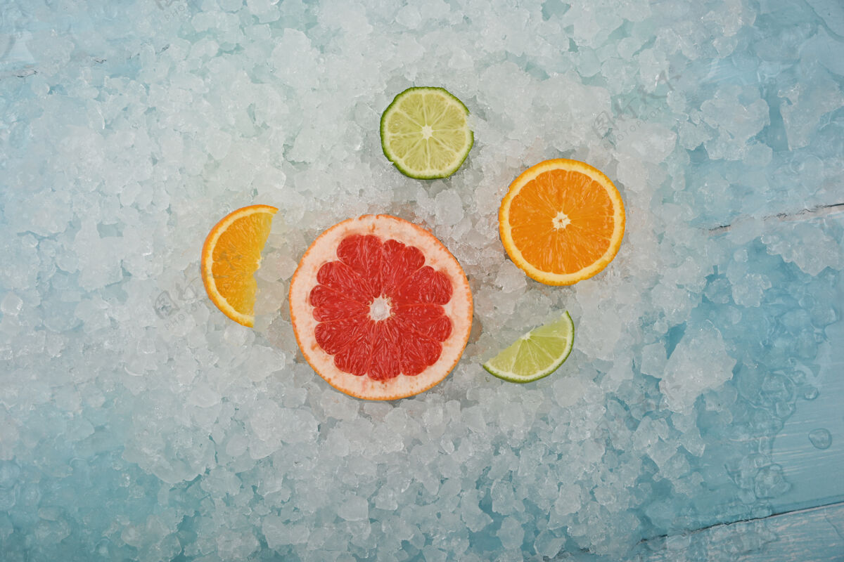 冷冻特写新鲜多汁的柑橘类水果片 粉红葡萄柚 橘子和青柠 背景是碎冰 高角度视角 正上方餐桌冷藏一半