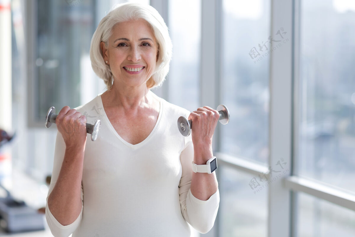 训练停留高级健身教练苗条的女人微笑着在健身房锻炼时举重快乐能量决心
