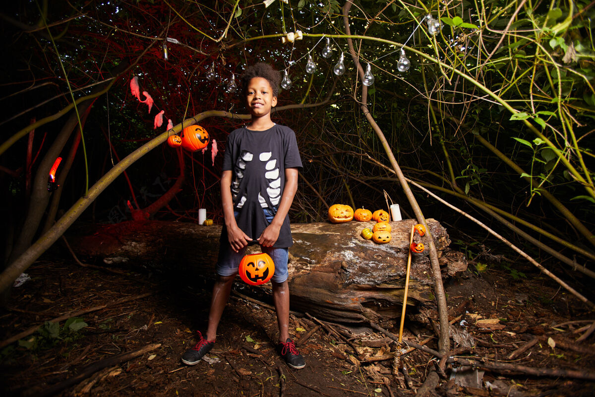 橙色在黑暗的户外参观万圣节派对时非洲男孩的画像叶子运动季节