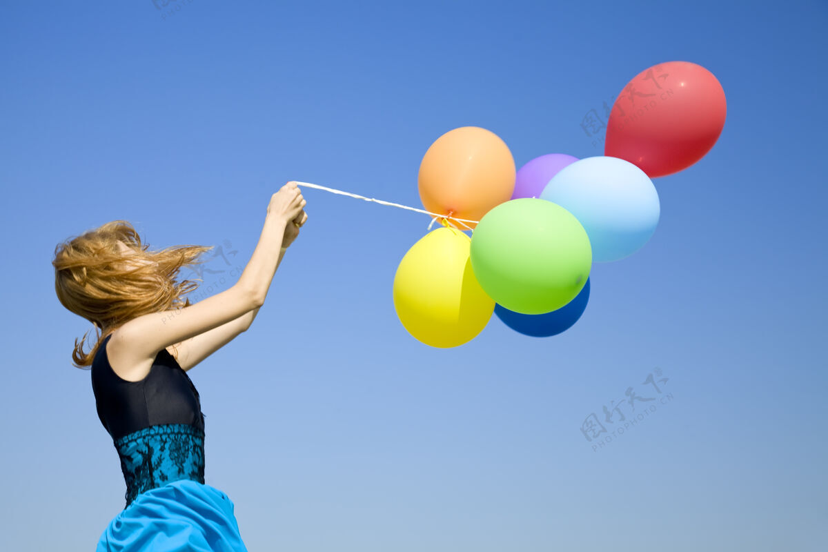 跑步红发女孩带着彩色气球在蓝天上游戏红发海岸