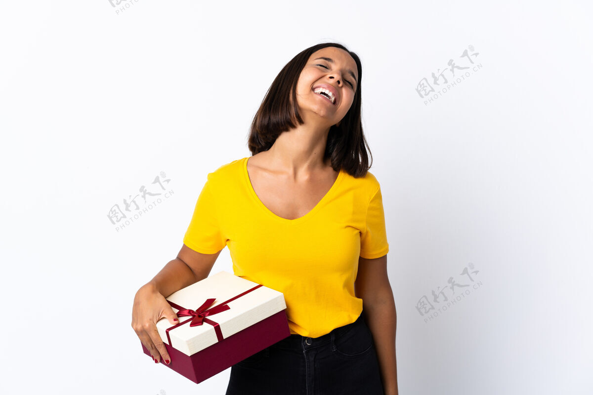 乐趣年轻的拉丁女人拿着一件礼物 笑得白白的成人骄傲礼物