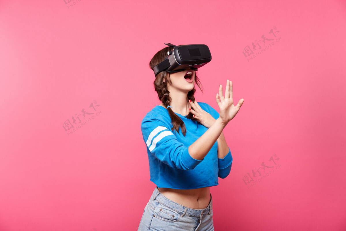 虚拟现实漂亮的年轻女孩在粉红色的墙上摆姿势肖像漂亮手机