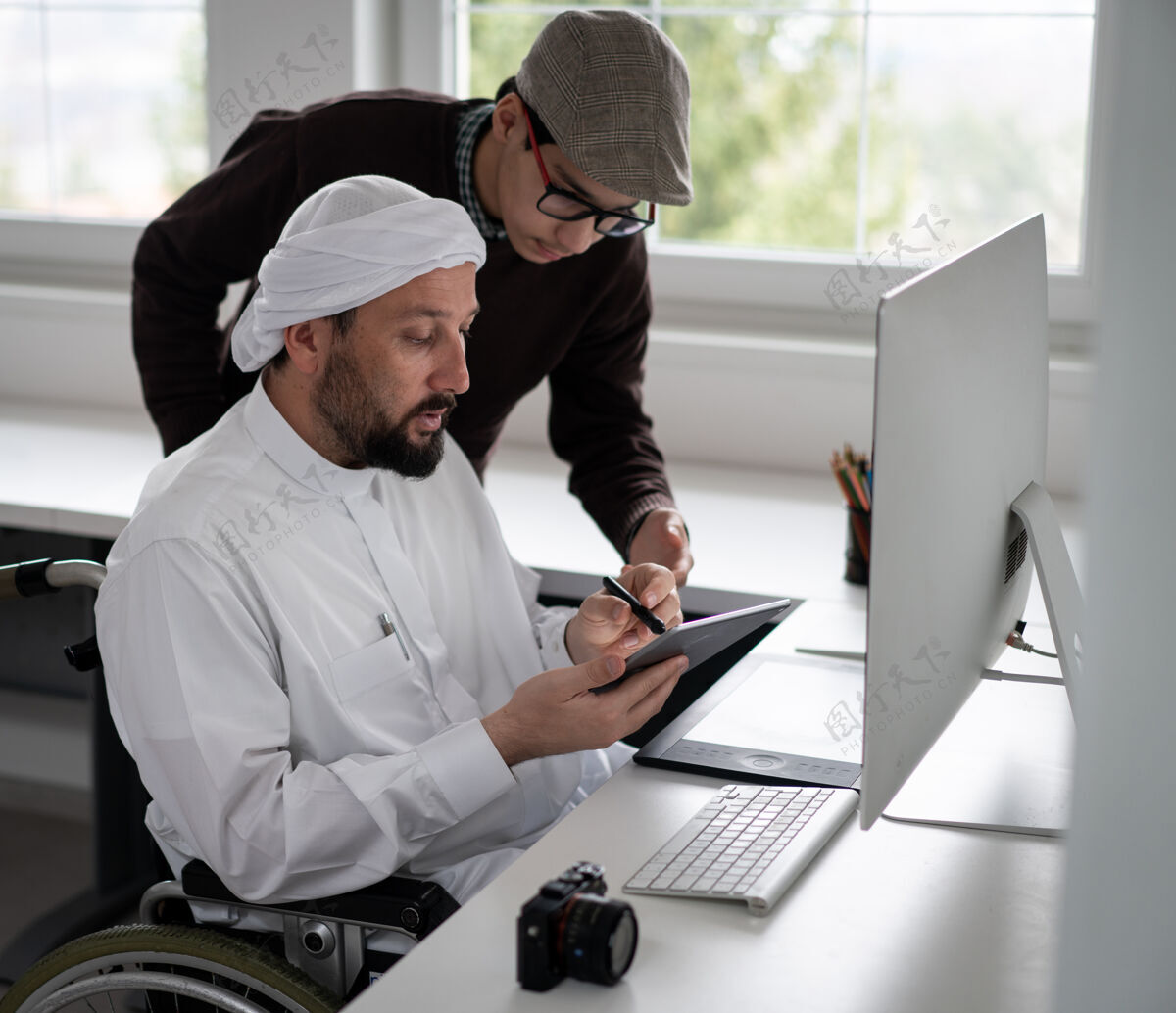 家庭办公室坐在轮椅上的阿拉伯男人坐在办公桌旁 手里拿着电脑残疾办公室多样性