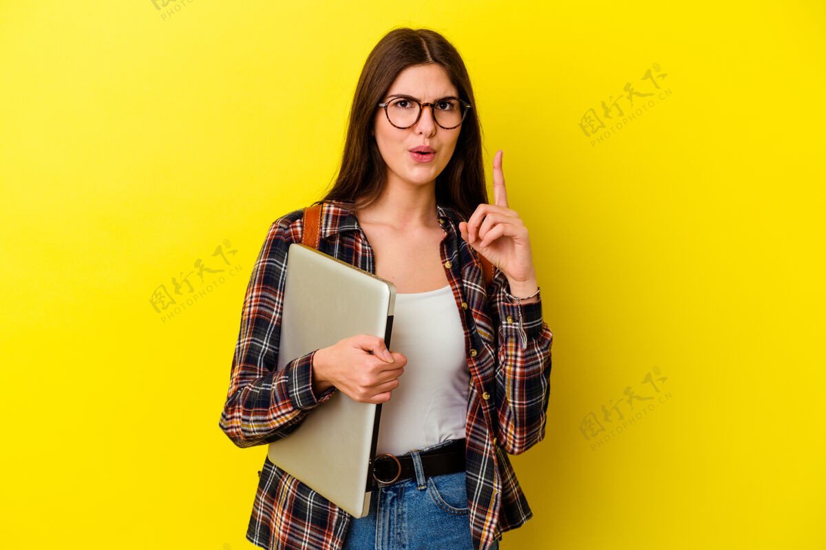 成功年轻的白人女学生拿着一台笔记本电脑 背景是粉红色的 她有一些伟大的想法 创意的概念教育学习学习者