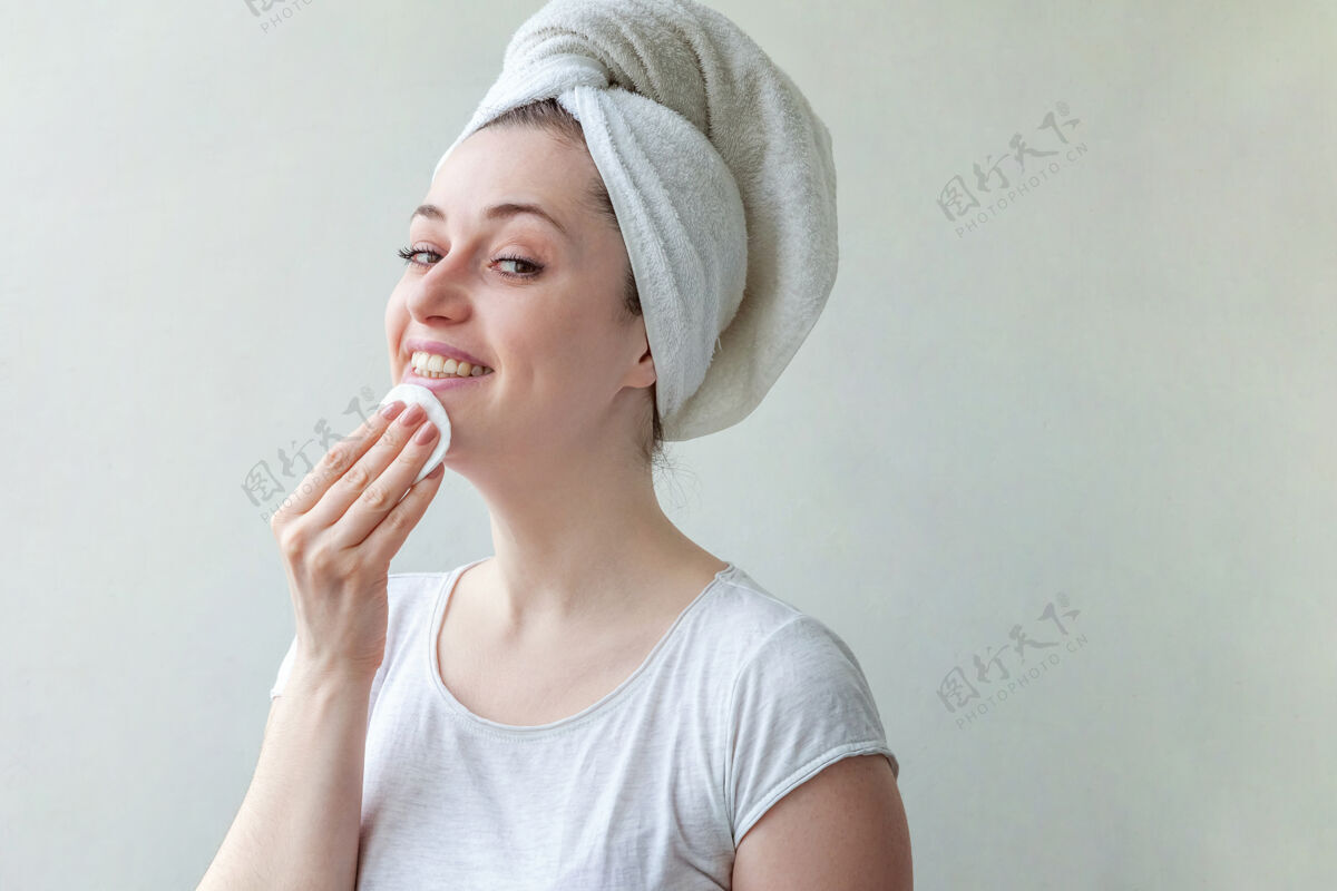 水化头上戴着毛巾的微笑女人的美丽肖像 柔软健康的皮肤 用隔离在白色背景上的化妆棉卸妆应用Maquillage触摸