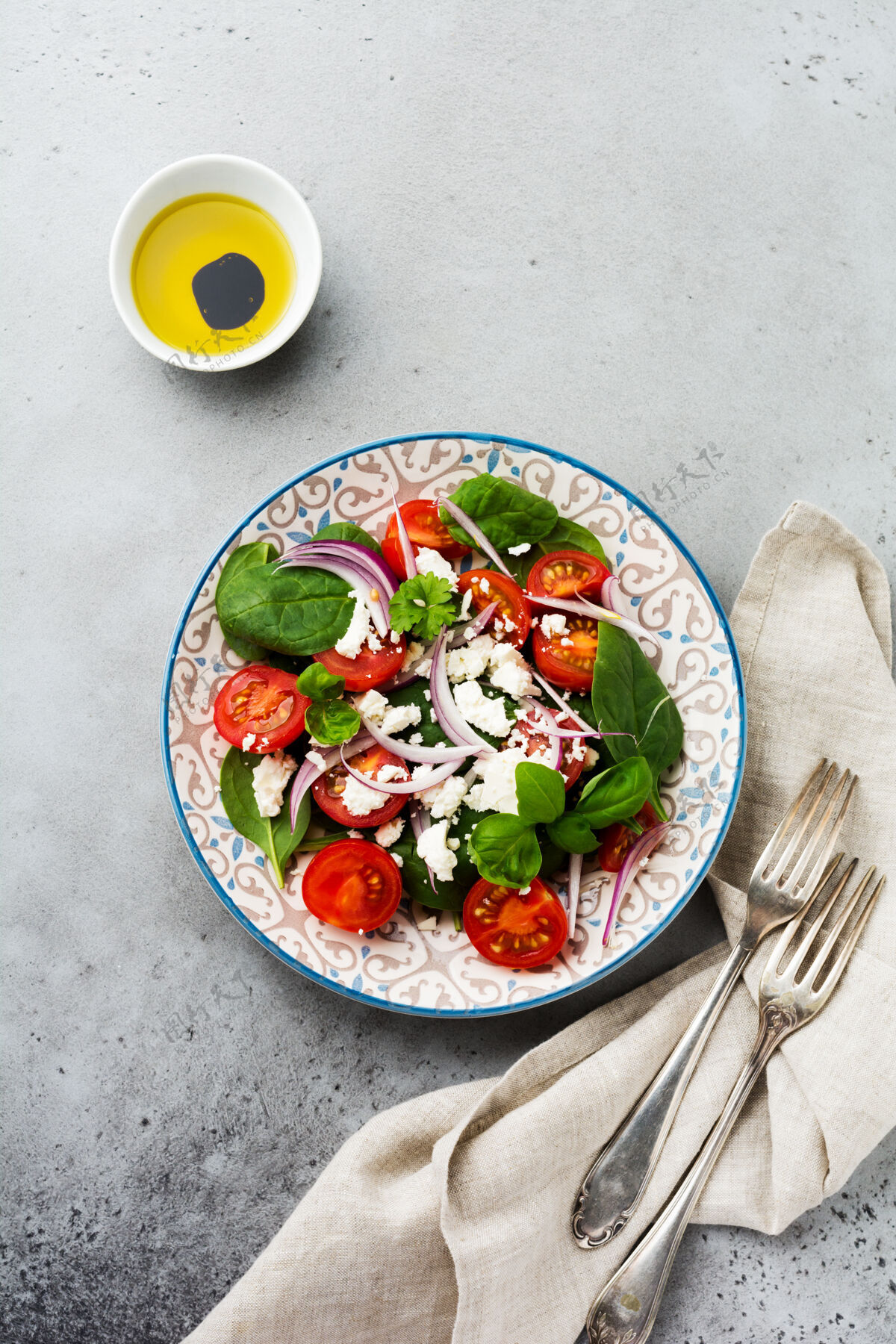 盘子西红柿 菠菜叶 红洋葱和羊乳酪沙拉放在浅色陶瓷盘子里 灰色的背面素食沙拉使用
