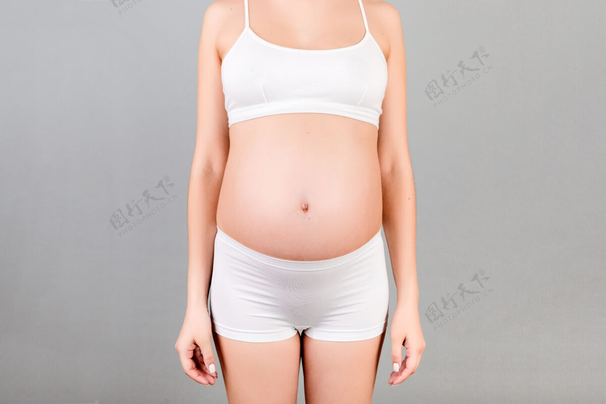 胎儿孕妇穿着灰色背景的白色内衣积极性成人腹部
