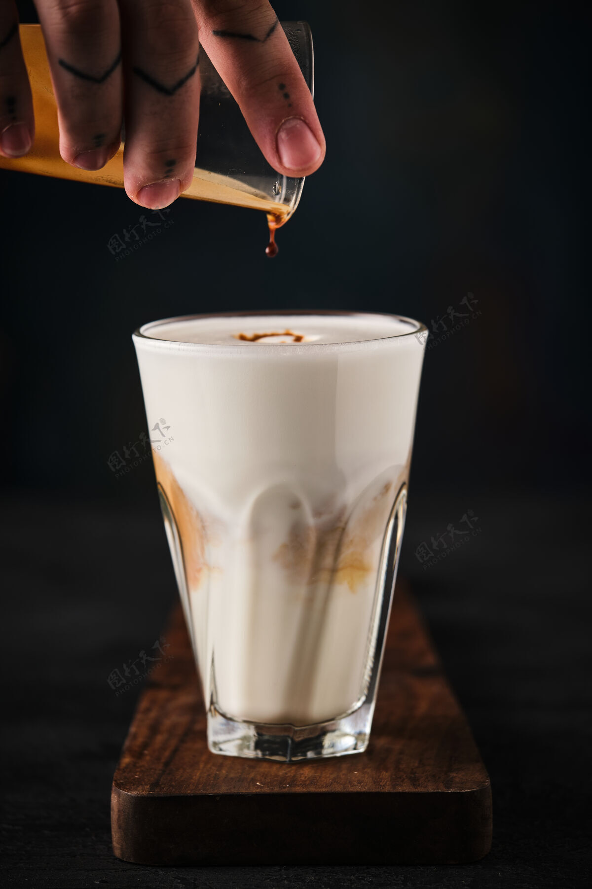 牛奶一杯平淡的白咖啡放在木头上董事会他的手把咖啡倒进杯子里泡沫美食饮料